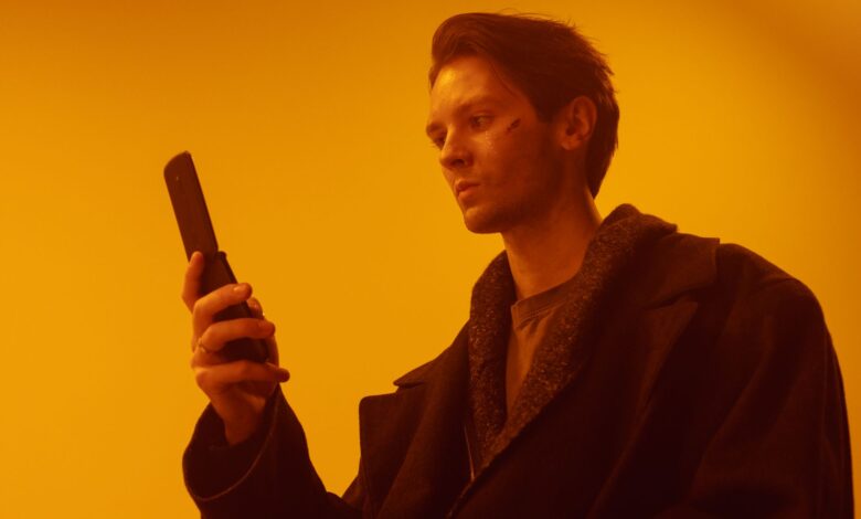 Dramatic studio portrait of a man using a vintage flip phone.