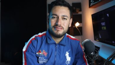 Man in a blue jacket with microphone recording a podcast in a home studio setup.