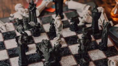 Close-up of intricately designed chess pieces on a marble-patterned board.
