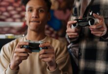 Two young adults intensely focused on playing video games with controllers indoors.
