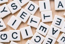 Closeup of scattered scrabble tiles against a wooden background, ideal for word games and learning themes.