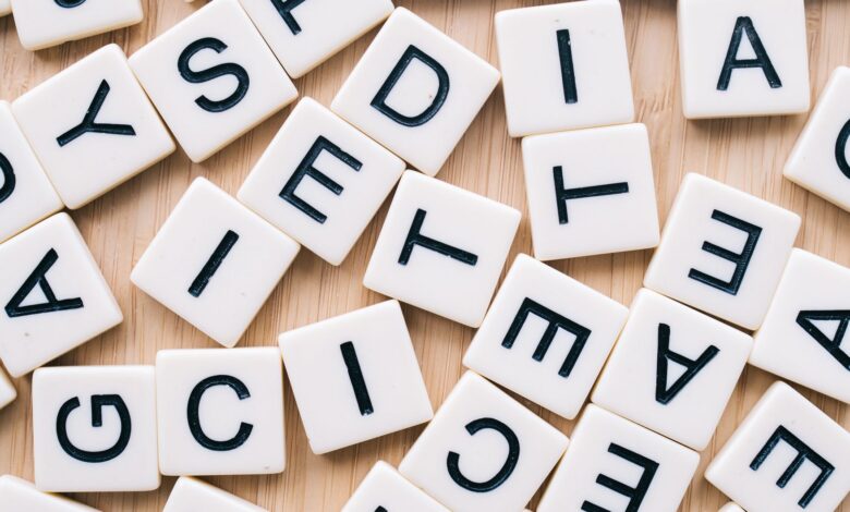 Closeup of scattered scrabble tiles against a wooden background, ideal for word games and learning themes.