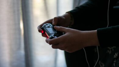 Close-up of hands holding a video game controller in a dimly lit room.