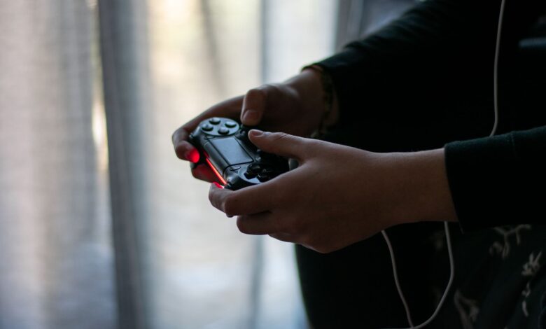 Close-up of hands holding a video game controller in a dimly lit room.