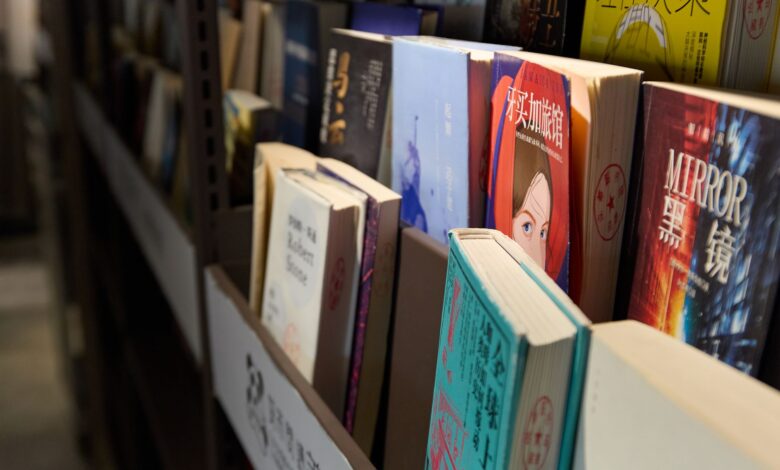 Books neatly arranged on a library shelf, showcasing a variety of genres and languages.