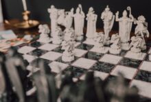 Stylized close-up of a themed chess set with unique, artistic figures on a marble board.