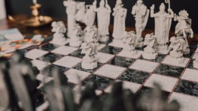 Stylized close-up of a themed chess set with unique, artistic figures on a marble board.