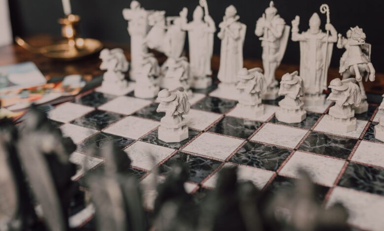 Stylized close-up of a themed chess set with unique, artistic figures on a marble board.
