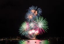 Colorful fireworks illuminate the night sky over Plymouth Harbor, creating a festive and vibrant atmosphere.