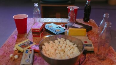 A nostalgic setup with popcorn, VHS tapes, and retro gaming consoles on a wooden table.