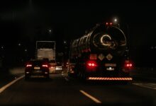 Vehicles drive down a dark highway at night, showcasing traffic and car lights.