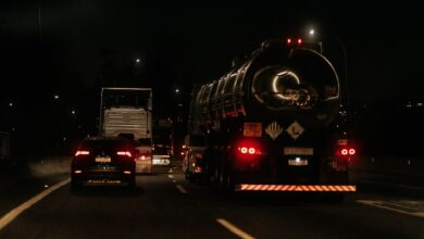 Vehicles drive down a dark highway at night, showcasing traffic and car lights.