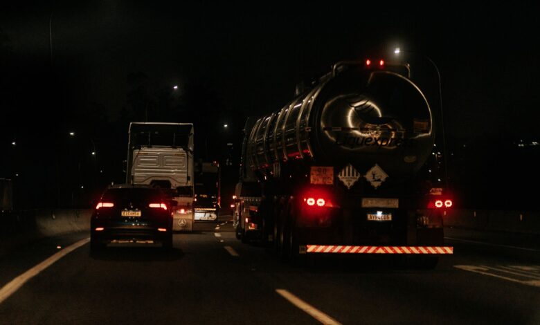 Vehicles drive down a dark highway at night, showcasing traffic and car lights.