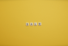 Single word 'SALE' spelled with tiles on a bright yellow background, ideal for advertising.