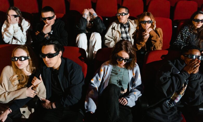 Group of people watching a movie in 3D glasses, expressing excitement and surprise.