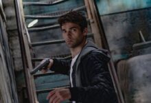 A man holding a gun in a dimly lit, mysterious urban setting.
