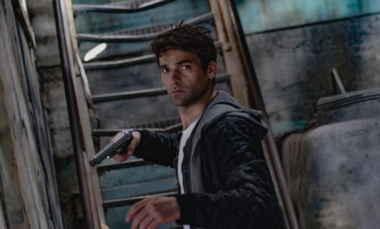 A man holding a gun in a dimly lit, mysterious urban setting.