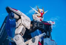 Close-up of a giant Gundam robot statue set against a clear blue sky.