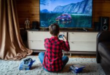 Boy in plaid shirt playing video games on console in a cozy living room setting.