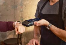 Smartwatch user making a contactless payment at a café using a POS device.