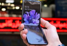 Close-up of a modern flip smartphone held in hand, showcasing innovative technology outdoors in a bustling city.