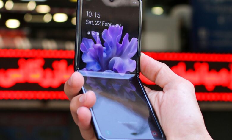 Close-up of a modern flip smartphone held in hand, showcasing innovative technology outdoors in a bustling city.