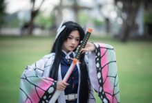 Cosplayer dressed as a character holding a sword in a park setting.