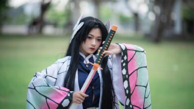 Cosplayer dressed as a character holding a sword in a park setting.