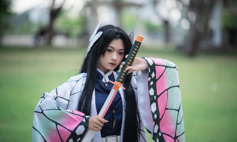 Cosplayer dressed as a character holding a sword in a park setting.
