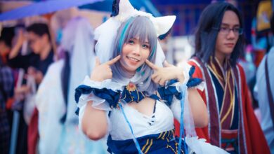 A cheerful cosplayer in a colorful anime costume poses at an outdoor event.