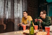 Two young men engaged in video gaming at home surrounded by snacks and drinks.