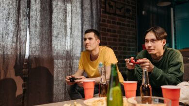 Two young men engaged in video gaming at home surrounded by snacks and drinks.