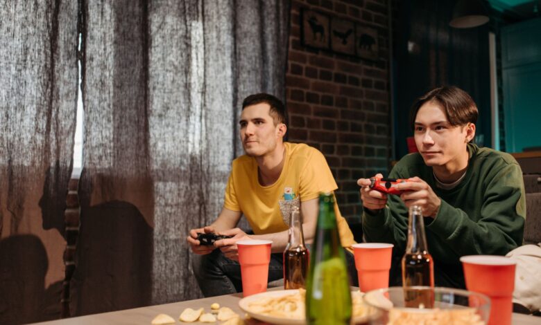 Two young men engaged in video gaming at home surrounded by snacks and drinks.