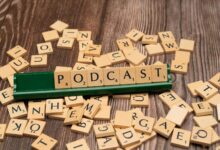 Wooden letter tiles on a board spelling the word 'Podcast', symbolizing digital media and creativity.