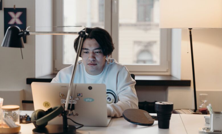Focused young man working at his desk with a laptop in a contemporary office.