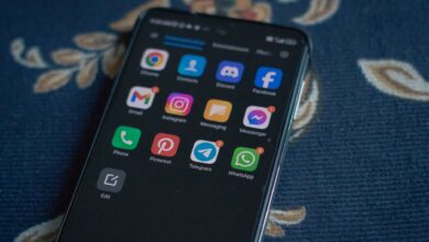 Close-up of a smartphone displaying popular social media apps on a floral fabric surface.