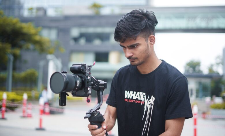A young filmmaker using a gimbal and camera setup outdoors for dynamic video shooting.