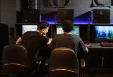 Two young men engaged in intense gaming session at an eSports venue. Computers and ambient lighting create an immersive experience.