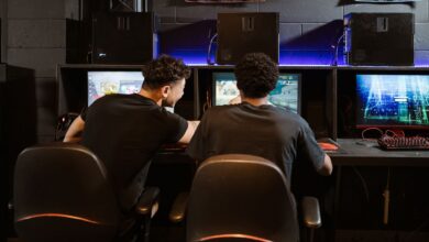 Two young men engaged in intense gaming session at an eSports venue. Computers and ambient lighting create an immersive experience.