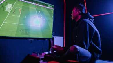 A young man enthusiastically playing video games on a console in a dimly lit gaming room.