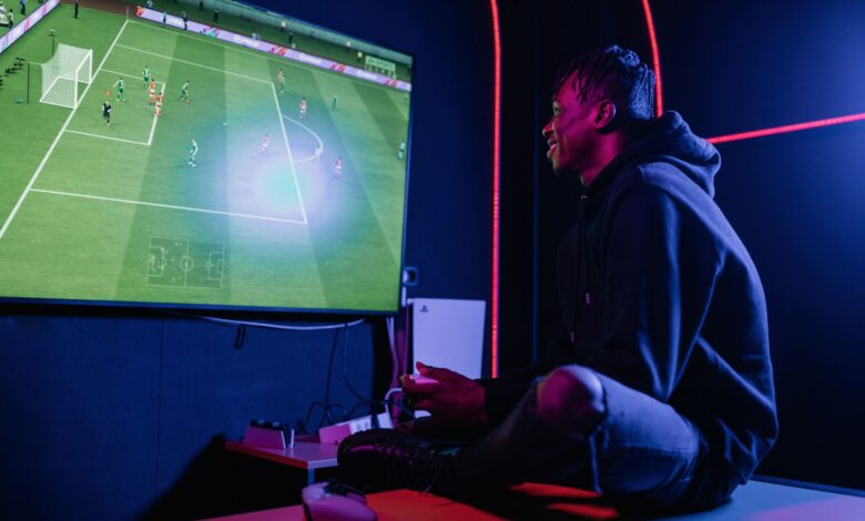 A young man enthusiastically playing video games on a console in a dimly lit gaming room.
