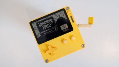 A yellow handheld gaming console featuring a crank handle on a white background.