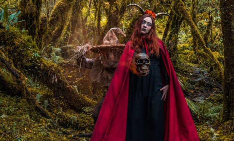 A woman in a witch costume with horns stands in a mystical forest in Colombia, holding a skull.