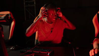 A young man enthusiastically gaming in a dimly lit room with headphones on.