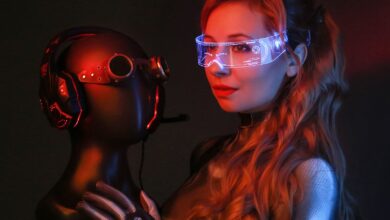 A woman in a sci-fi costume with goggles and gloves poses in a studio holding a mannequin head.