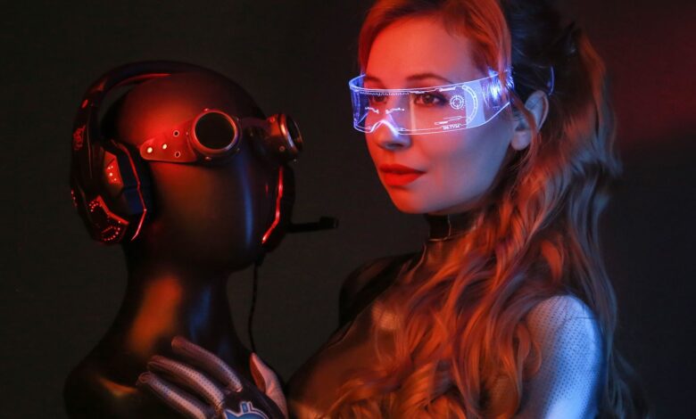 A woman in a sci-fi costume with goggles and gloves poses in a studio holding a mannequin head.