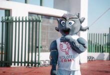 Lively team mascot in Ajolotes Lerma attire posing outdoors under a clear sky.