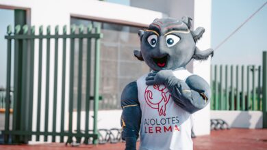 Lively team mascot in Ajolotes Lerma attire posing outdoors under a clear sky.