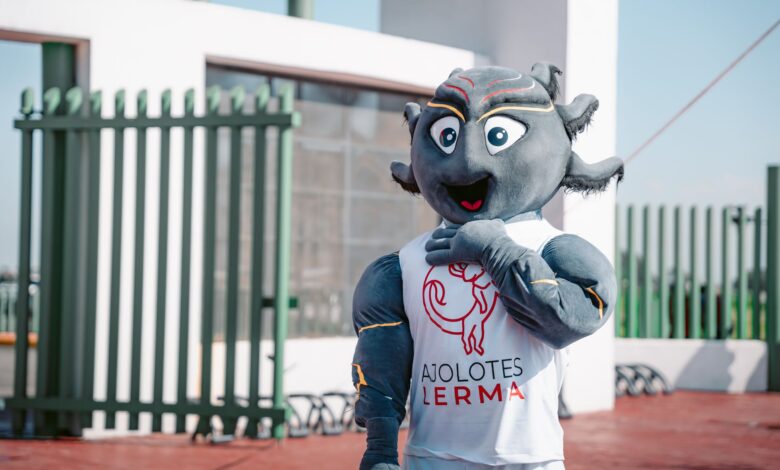 Lively team mascot in Ajolotes Lerma attire posing outdoors under a clear sky.