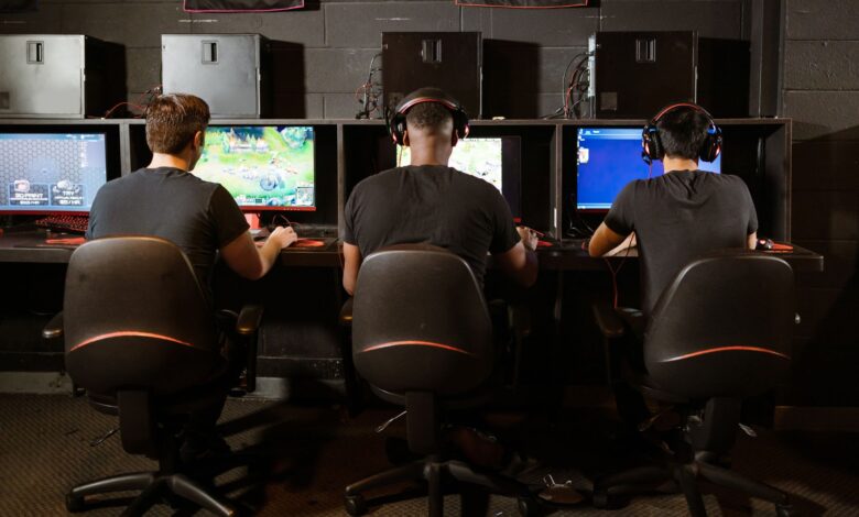 A group of men intensely focused on playing video games at a modern gaming arcade.